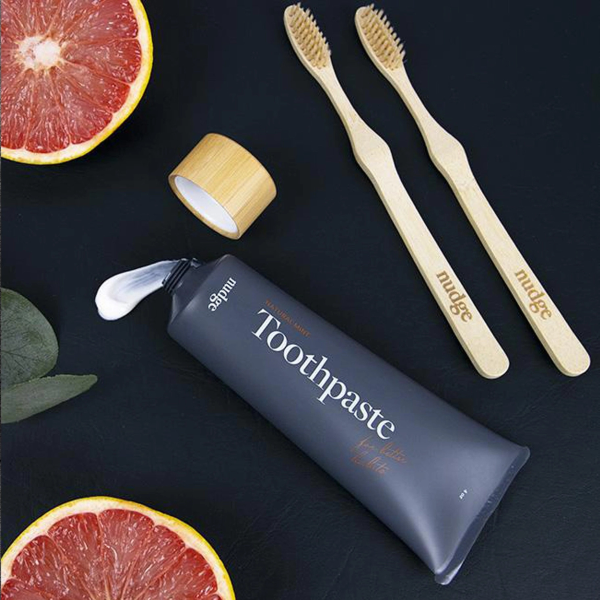nudge toothpaste with black background and natural toothbrush